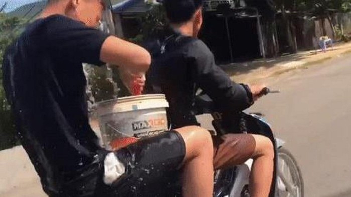 Hai thanh niên vừa điều khiển xe máy vừa gội đầu cho nhau
